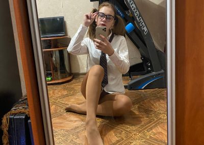 Young woman sitting in her pantyhose and school uniform taking selfie
