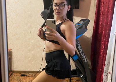 Girl in glasses wearing bra and skirt and pantyhose taking selfie