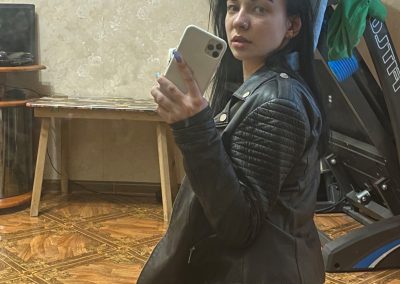 Bad girl in leather coat in black pantyhose taking selfie
