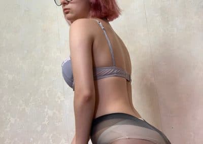 Pink hair girl wearing glasses on her knees in nylons