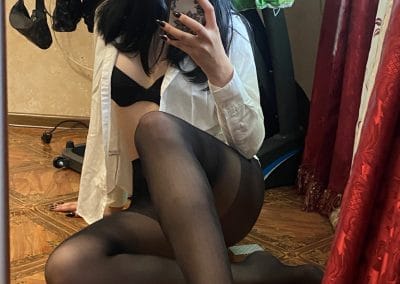 Tall Brunette wearing glasses on the floor taking selfie of her long legs in pantyhose