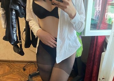 Sexy brunette wearing glasses and unbuttoned shirt and pantyhose taking selfie