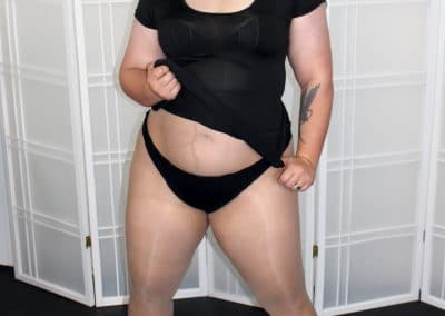 Chubby brunette with dress pulled up showing panties and pantyhose