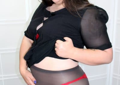 Sexy brunette lifting shirt to show waist in pantyhose and red panties